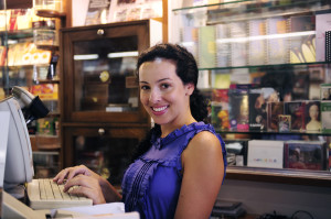 Woman shop owner standing in front of computer or register.