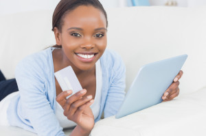 Happy customer with credit card making purchase on a tablet.